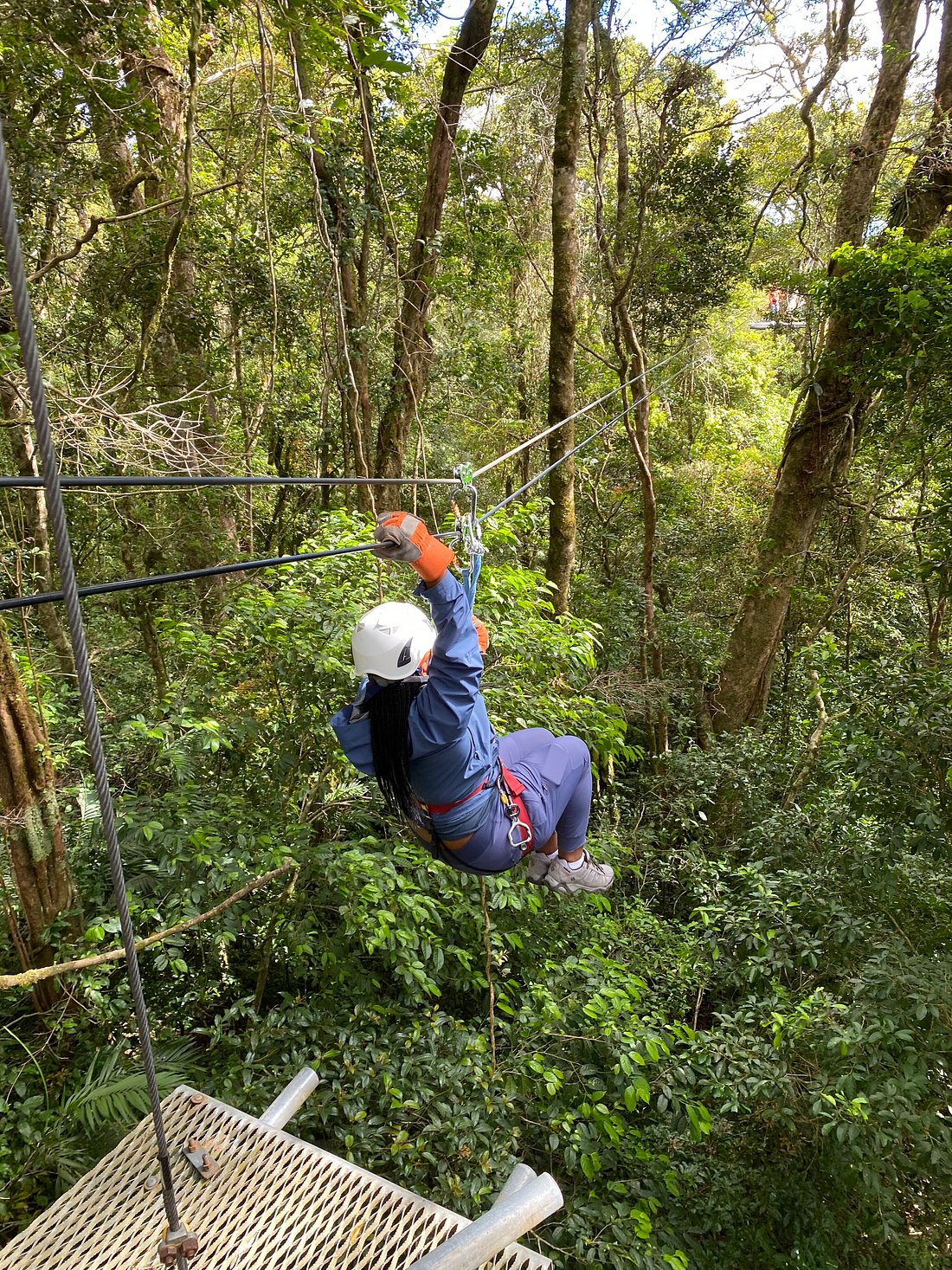 A scenic canopy tour above the Costa Rica rainforest with zipline riders moving across tall forest trees and panoramic jungle views.