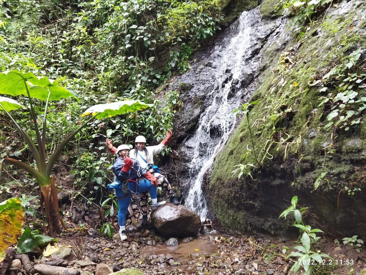 Visitors standing beside a rainforest waterfall in Costa Rica.