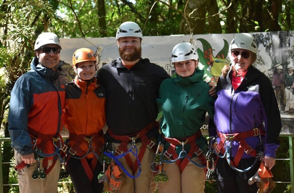 Five ziplining participants pose together on a forest platform in Costa Rica.