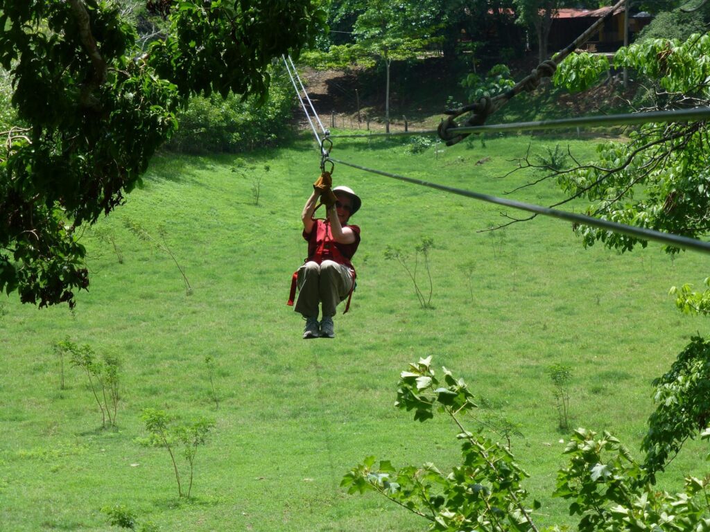 Person ziplining over a green Costa Rica canopy tour landscape surrounded by tropical trees.