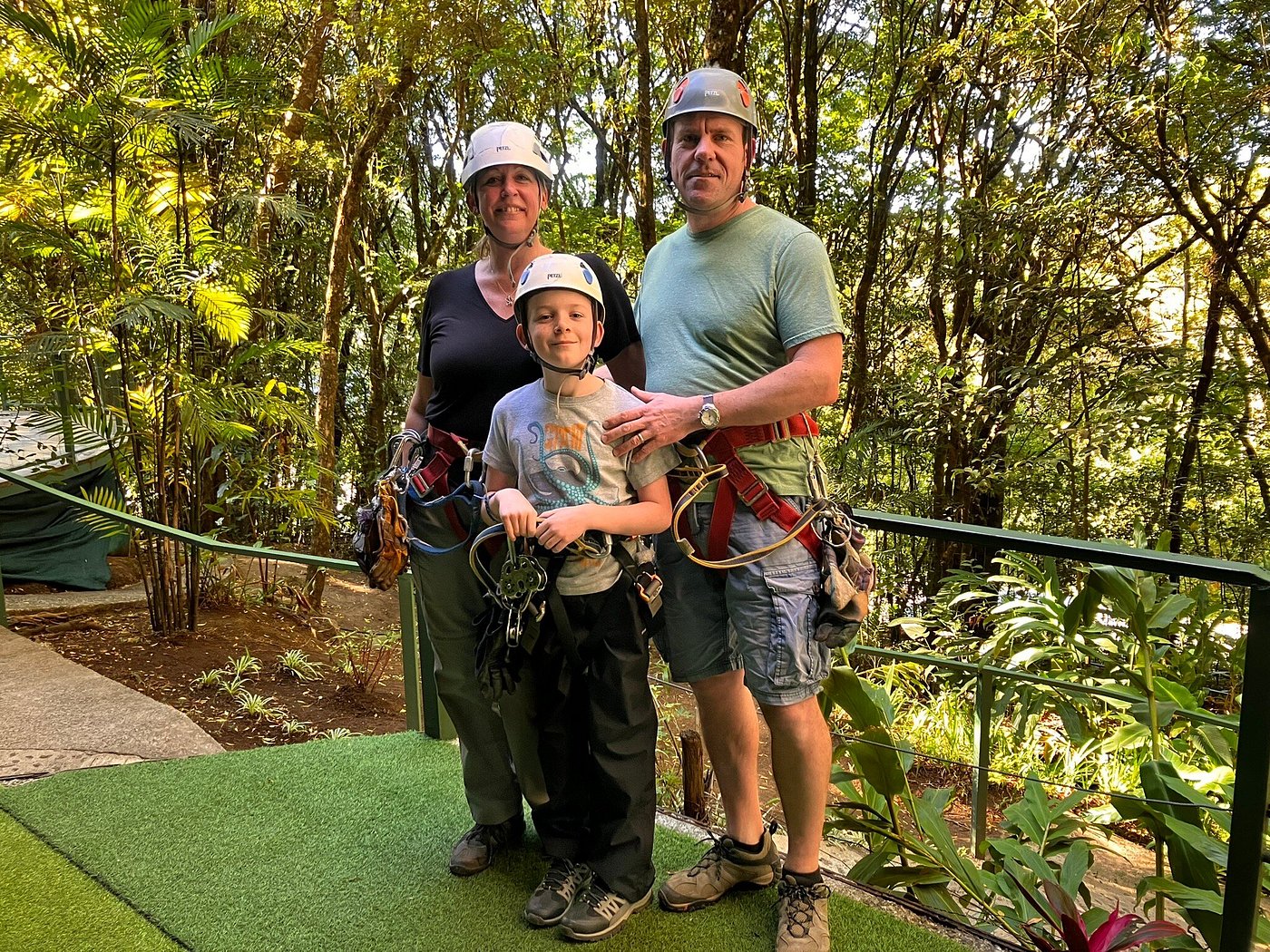 Family wearing helmets and ziplining harnesses pose together in a lush Costa Rican forest.