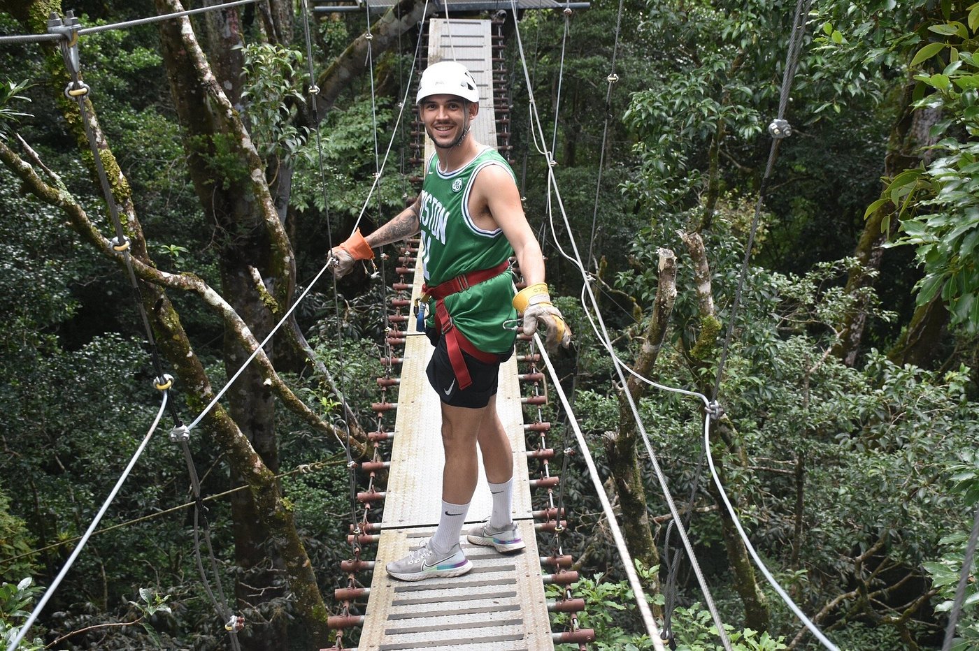 Traveler standing on a hanging bridge high in a dense tropical forest.