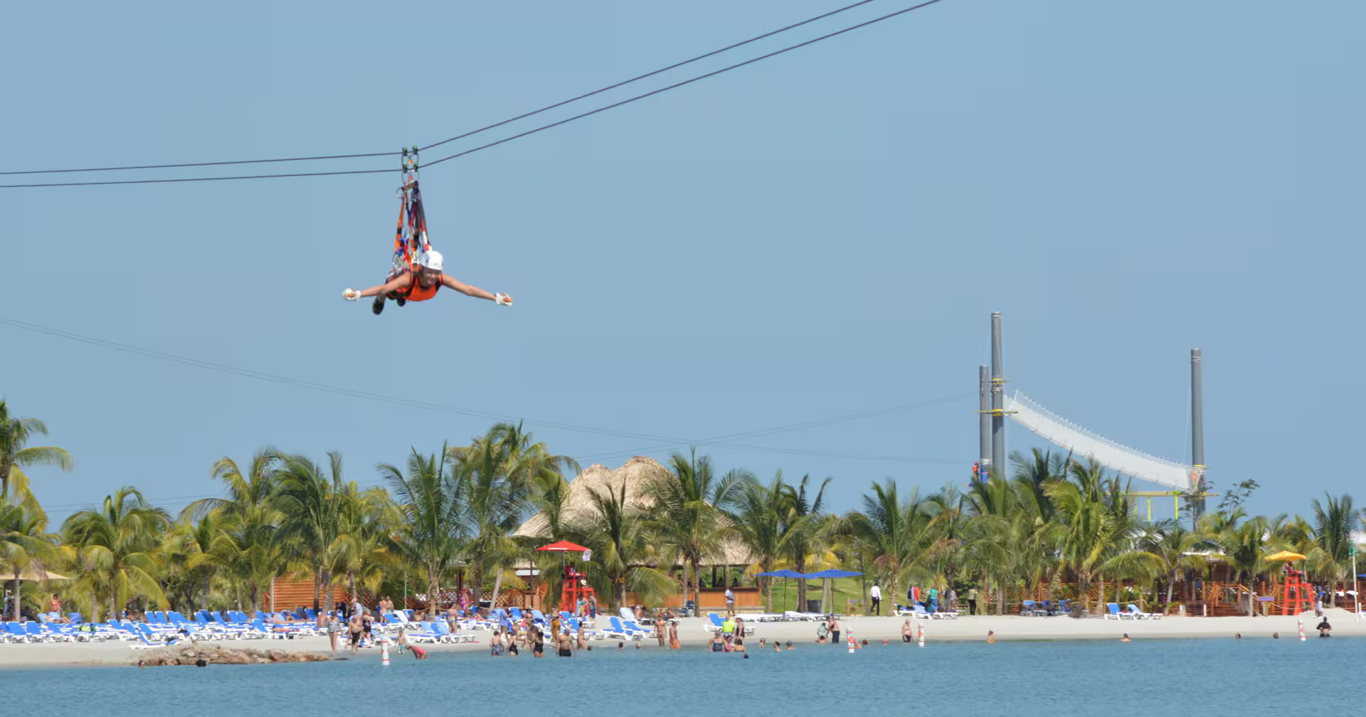 Zipline rider soars above turquoise lagoon and palm-lined Belize beach