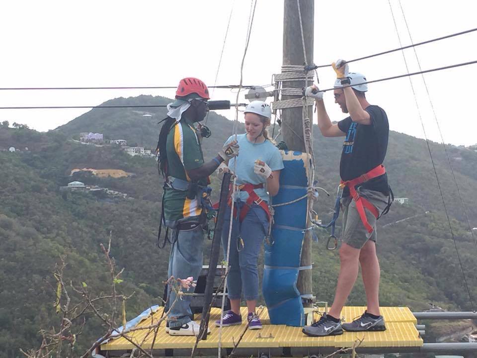 Guests wearing helmets and harnesses prepare to zipline in Tortola.