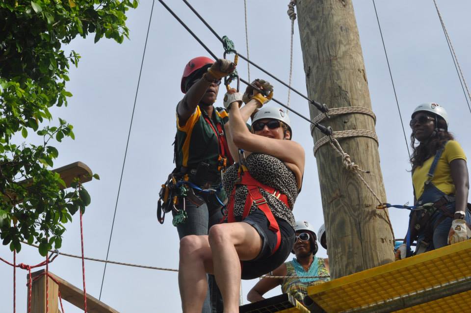 Guide helps a guest prepare for ziplining on an elevated platform.