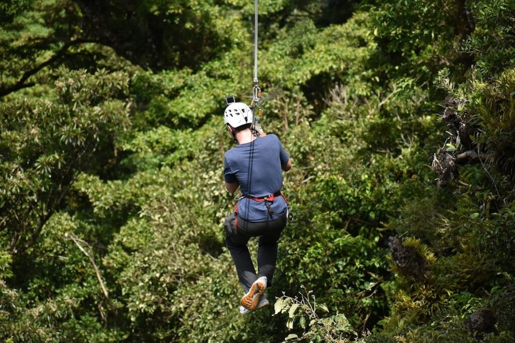 Traveler riding a zipline above the lush Monteverde cloud forest.