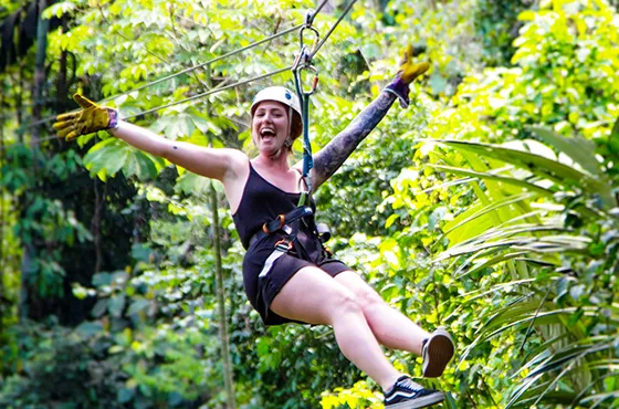 Woman ziplining through lush tropical rainforest in Costa Rica.